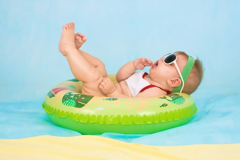 A baby wearing sunglasses on a colourful inflatable ring